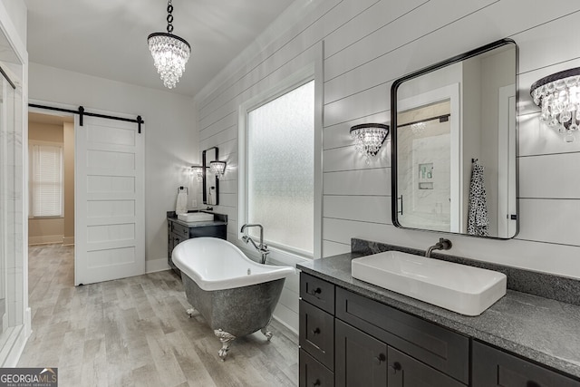 4621 Stanley Rd, Flowery Branch, GA 30542 - bathroom with a chandelier, wood finished floors, a freestanding tub, and two vanities