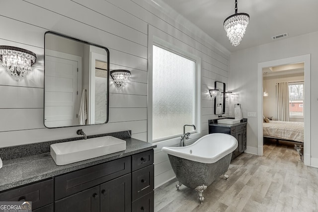 4621 Stanley Rd, Flowery Branch, GA 30542 - ensuite bathroom featuring a chandelier, wood finished floors, a soaking tub, and two vanities