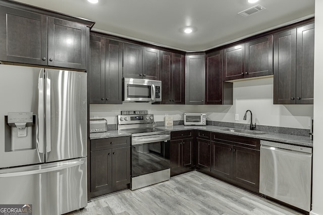 4621 Stanley Rd, Flowery Branch, GA 30542 - kitchen featuring stainless steel appliances, a sink, light wood finished floors, dark brown cabinetry, and recessed lighting