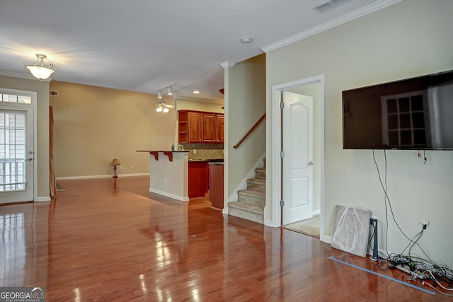 unfurnished living room with ceiling fan, ornamental molding, and hardwood / wood-style flooring