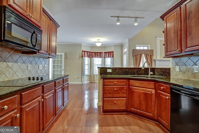 kitchen with light hardwood / wood-style floors, decorative backsplash, dark stone counters, black appliances, and sink