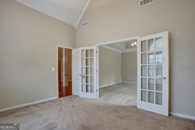 carpeted empty room with high vaulted ceiling, ceiling fan, crown molding, and french doors