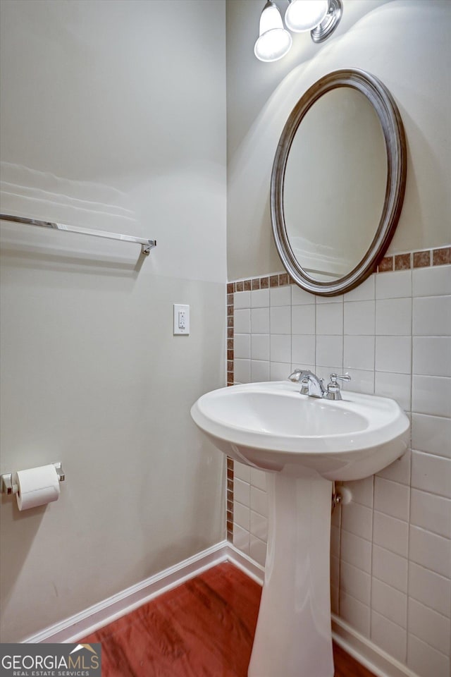 bathroom with hardwood / wood-style flooring, sink, and tile walls