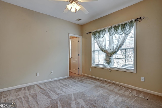 spare room with ceiling fan, light colored carpet, and plenty of natural light