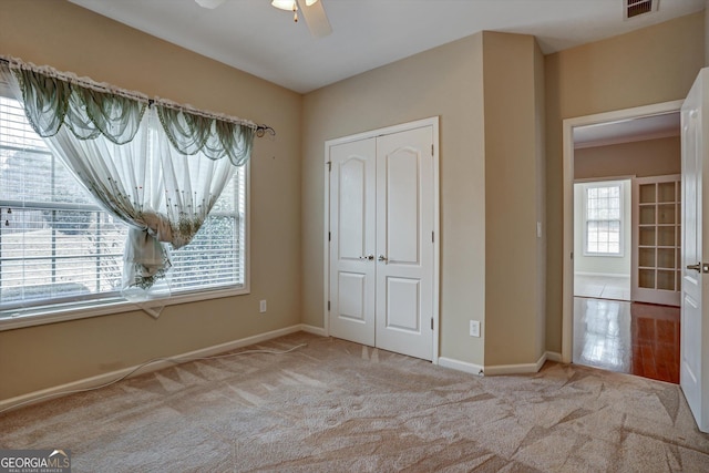 unfurnished bedroom with ceiling fan, a closet, and light carpet