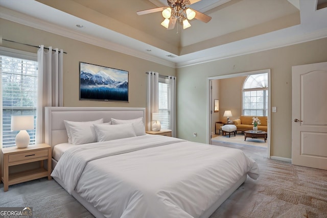 bedroom featuring ceiling fan, light colored carpet, ornamental molding, and a raised ceiling