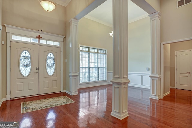 foyer featuring hardwood / wood-style floors, ornamental molding, and decorative columns