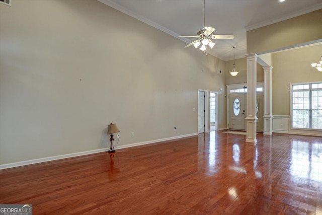 foyer entrance with wood-type flooring, ceiling fan with notable chandelier, ornamental molding, and ornate columns