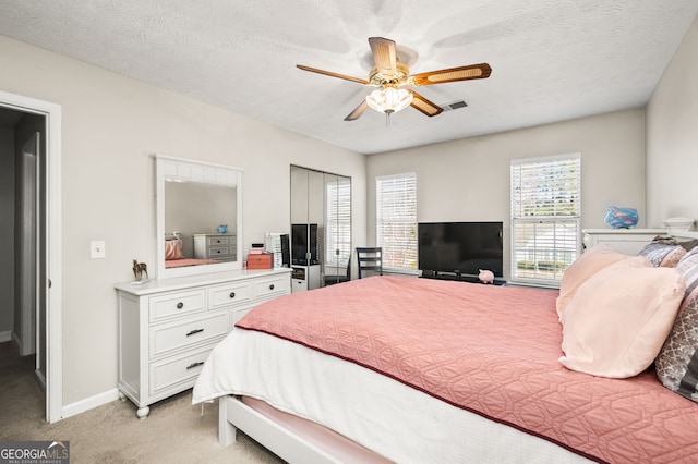 carpeted bedroom featuring ceiling fan and a textured ceiling