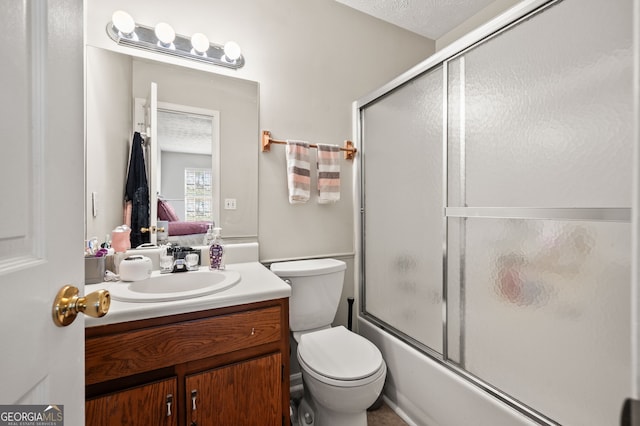 full bathroom with vanity, toilet, combined bath / shower with glass door, and a textured ceiling