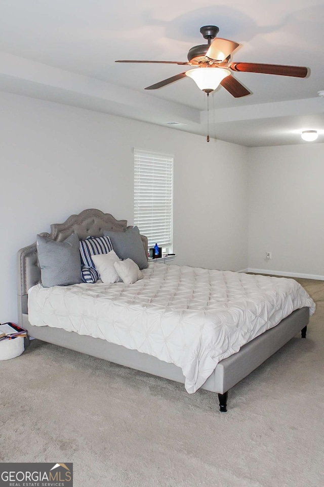 bedroom with ceiling fan, a raised ceiling, and carpet floors