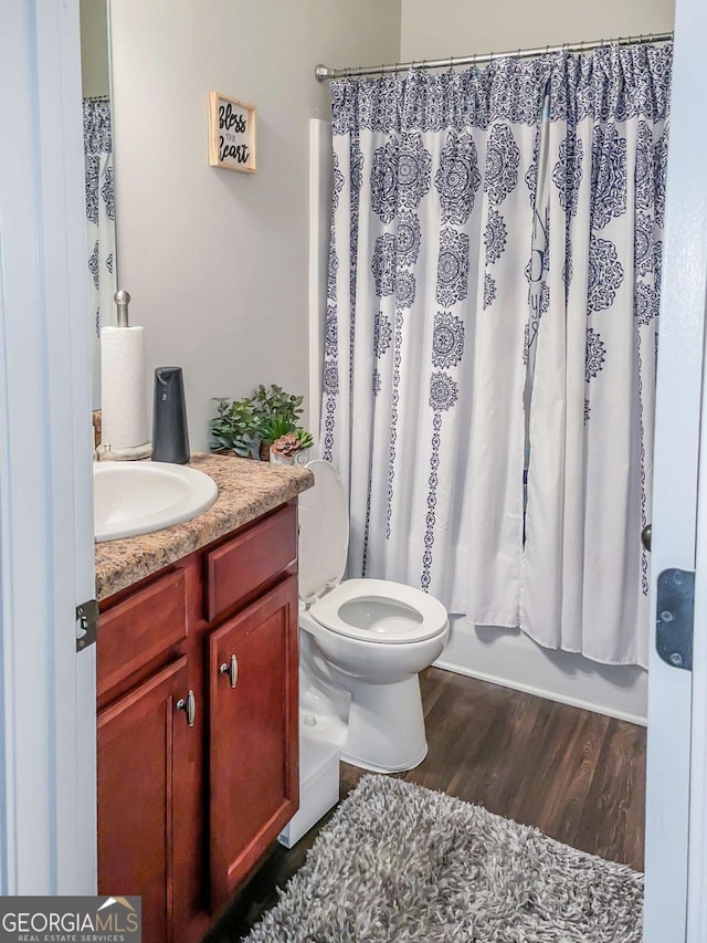 full bathroom featuring shower / bath combo with shower curtain, hardwood / wood-style floors, toilet, and vanity