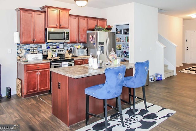 kitchen with a breakfast bar area, dark hardwood / wood-style flooring, stainless steel appliances, and a center island