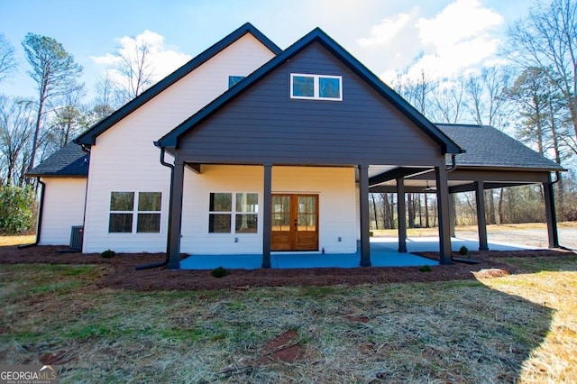 back of house featuring a shingled roof, a lawn, and a patio area