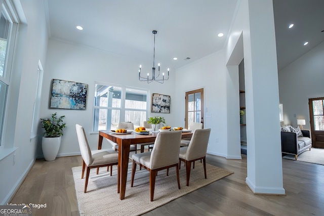 dining space featuring a chandelier, a towering ceiling, hardwood / wood-style flooring, and ornamental molding