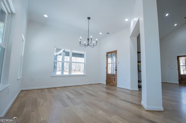 interior space featuring light hardwood / wood-style floors, a high ceiling, ornamental molding, and a chandelier