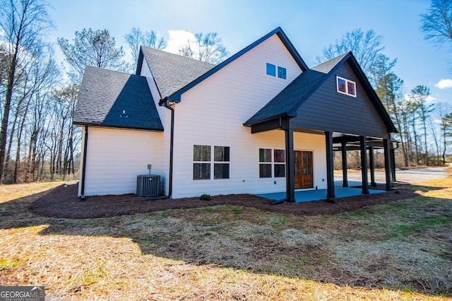 rear view of property with a shingled roof, a patio area, and central air condition unit