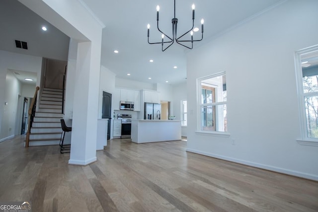 unfurnished living room featuring light wood-style flooring, plenty of natural light, stairway, and baseboards