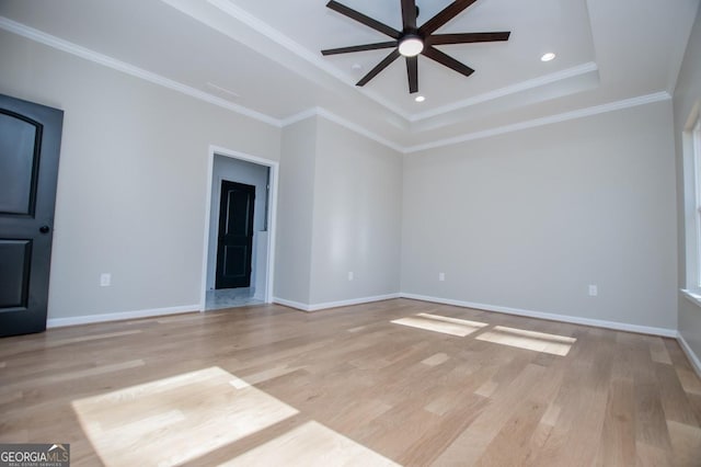 unfurnished room with ceiling fan, ornamental molding, light hardwood / wood-style floors, and a raised ceiling