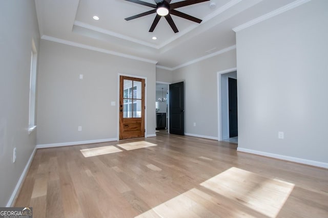 interior space with light wood finished floors, baseboards, and a raised ceiling