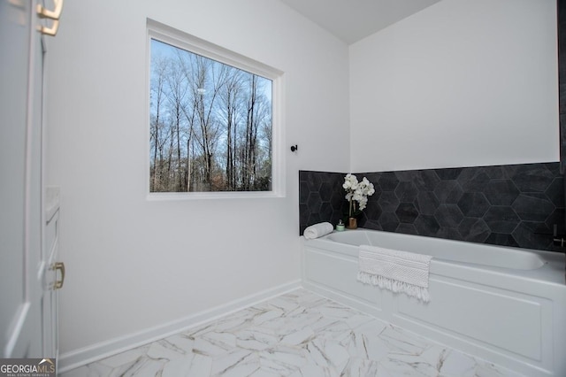 full bathroom with marble finish floor, baseboards, and a bath