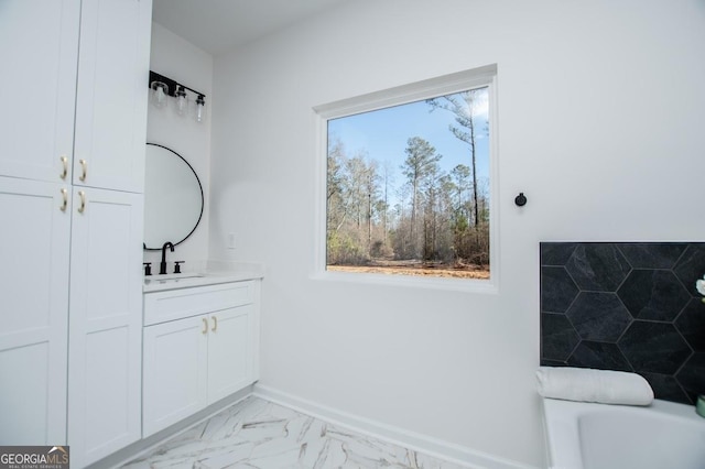 full bathroom with a tub to relax in, marble finish floor, baseboards, and vanity