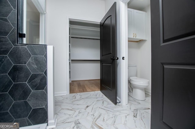 full bathroom with marble finish floor, toilet, and baseboards