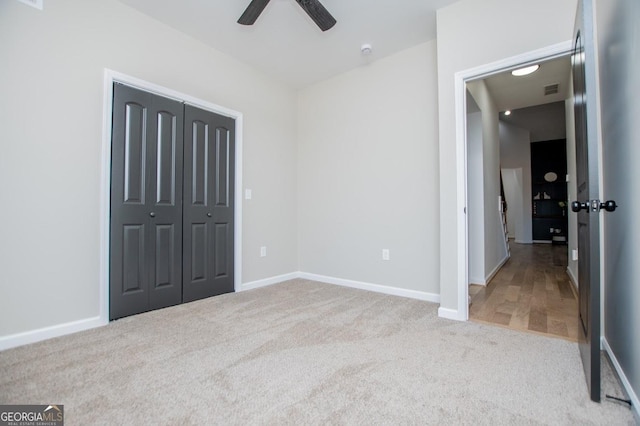 unfurnished bedroom with ceiling fan, a closet, and light carpet