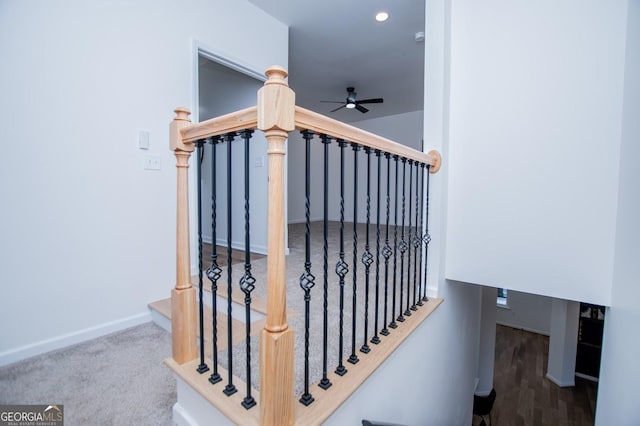 staircase with ceiling fan and carpet floors