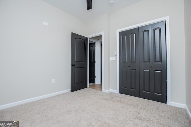 unfurnished bedroom featuring carpet floors, a closet, baseboards, and a ceiling fan