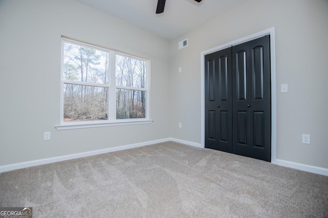 unfurnished bedroom with ceiling fan, visible vents, baseboards, a closet, and carpet