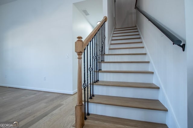 stairs featuring visible vents, baseboards, and wood finished floors