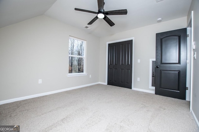 unfurnished bedroom featuring visible vents, baseboards, vaulted ceiling, a closet, and carpet