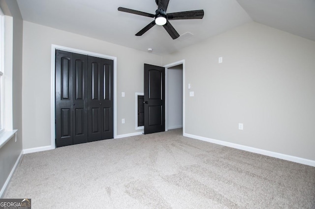 unfurnished bedroom with a closet, carpet flooring, vaulted ceiling, and baseboards