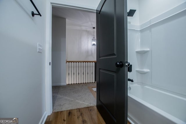 bathroom featuring washtub / shower combination and wood finished floors