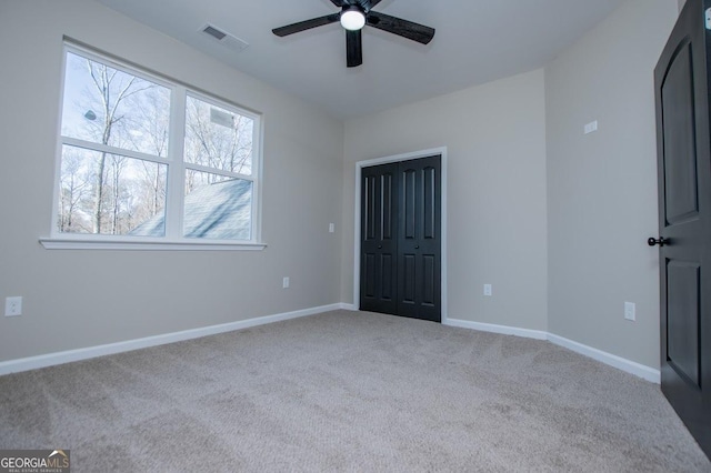 unfurnished bedroom with ceiling fan, a closet, carpet flooring, and baseboards