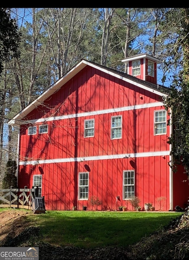 view of side of property with fence, board and batten siding, and a yard