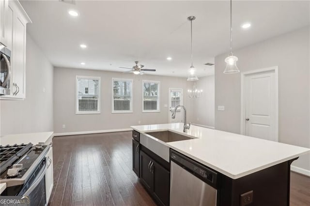 kitchen with a center island with sink, appliances with stainless steel finishes, dark hardwood / wood-style flooring, hanging light fixtures, and sink