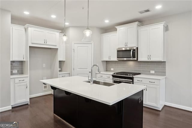 kitchen with white cabinetry, an island with sink, stainless steel appliances, decorative light fixtures, and sink