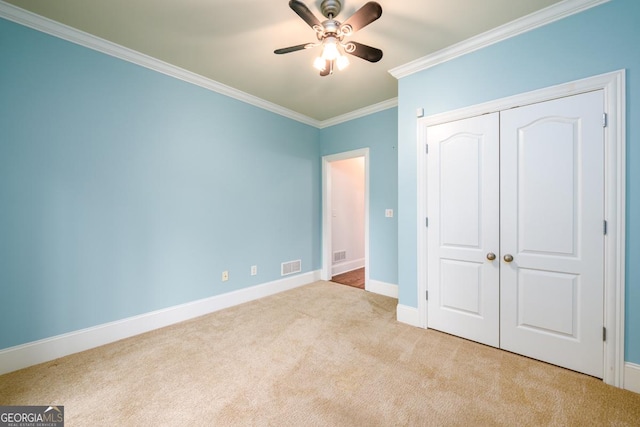 unfurnished bedroom featuring crown molding, light carpet, a closet, and ceiling fan