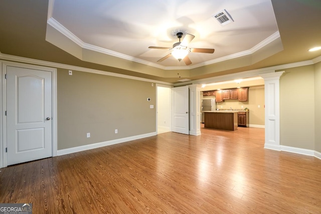 unfurnished living room with ceiling fan, crown molding, light hardwood / wood-style floors, and a tray ceiling