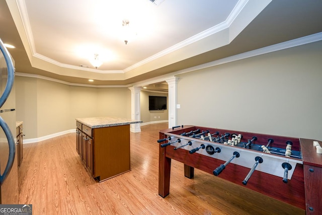 playroom featuring decorative columns, a tray ceiling, and ornamental molding