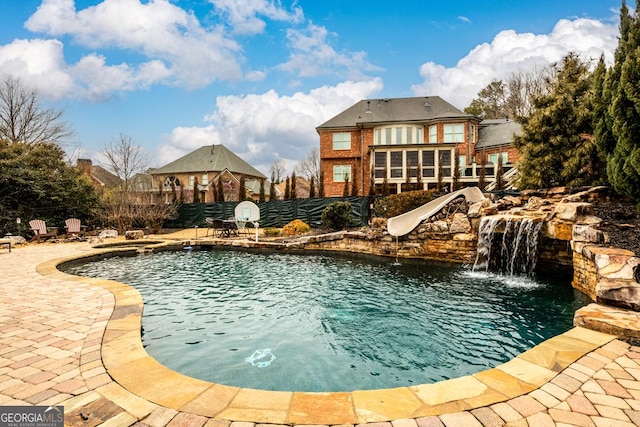 view of swimming pool featuring pool water feature, a patio area, and a water slide