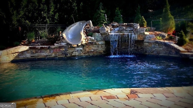 view of pool with a water slide and pool water feature