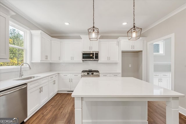 kitchen with appliances with stainless steel finishes, pendant lighting, white cabinetry, and sink