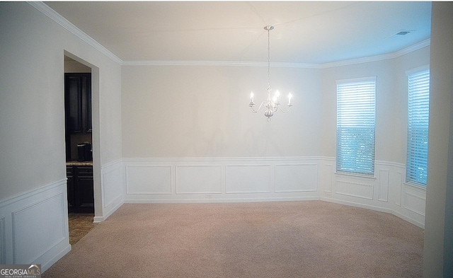 empty room with an inviting chandelier, ornamental molding, and carpet flooring