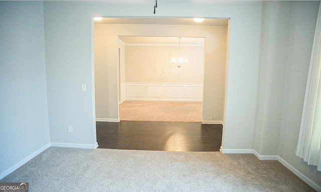 interior space with dark colored carpet, ornamental molding, and a notable chandelier