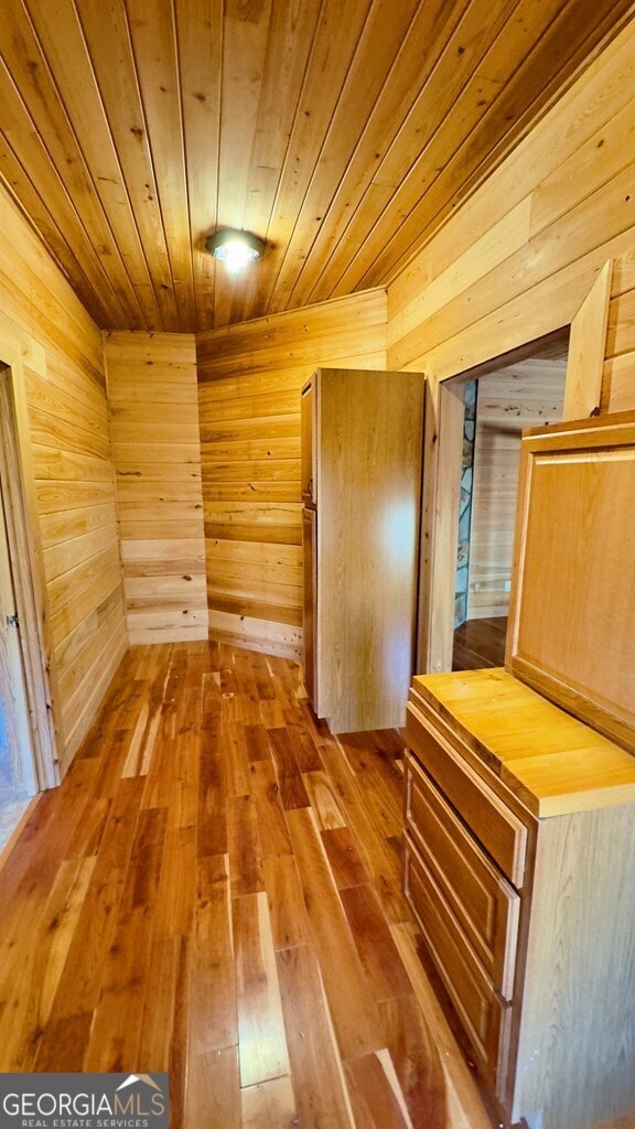 corridor with wood-type flooring, wooden ceiling, and wooden walls