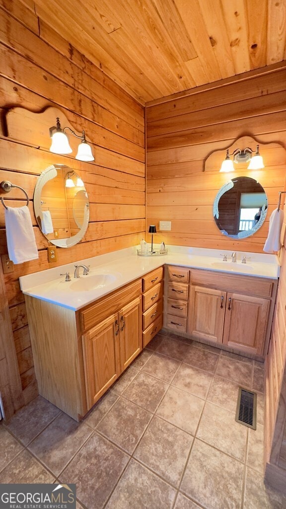 full bath featuring wooden walls, visible vents, wood ceiling, tile patterned floors, and vanity