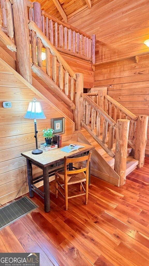 interior space with stairs, hardwood / wood-style floors, wood walls, and visible vents